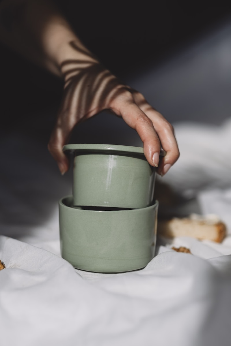 Bàn tay cầm hũ mỹ phẩm sứ màu xanh sage